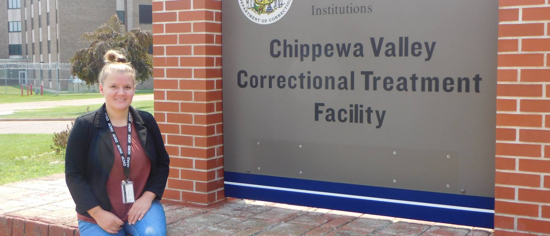 female student seated in front of signage at the Chippewa Valley Correctional Treatment Facility
