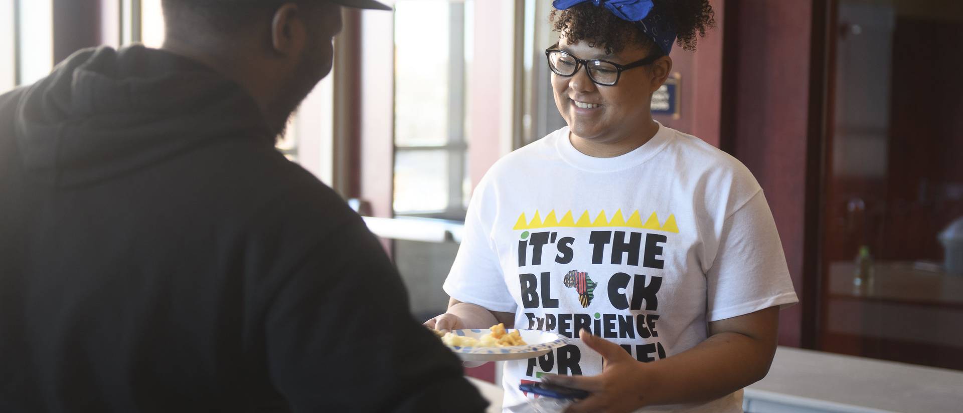 female student serving guests at a food-related celebration in Davies Center