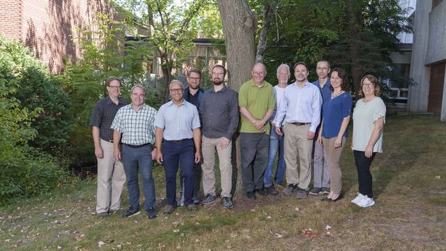 The faculty and staff of the department of physics and astronomy poses outside Phillips Hall.