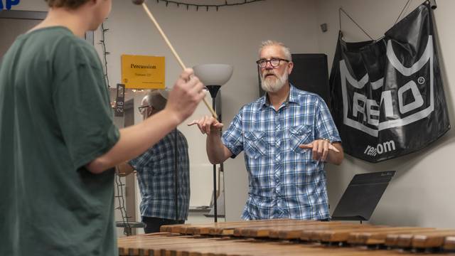 Jeffrey Crowell, music profesor, in a small group percussion lesson in Haas Fine Arts with two students, one make and one female.