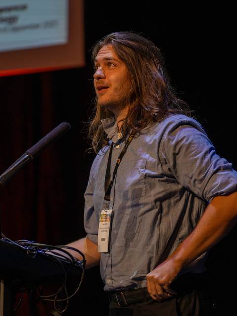 Reed Oberg presenting his research at a podium.