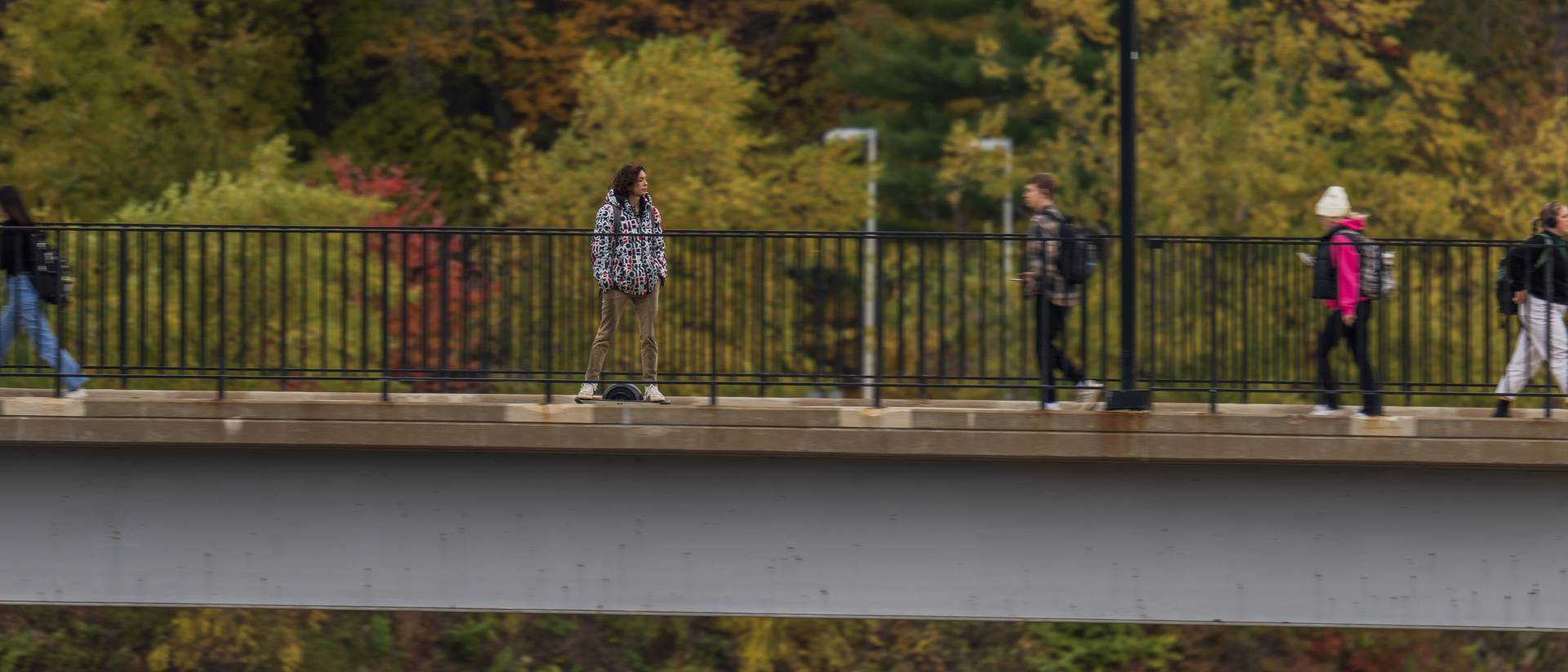 one wheel device rider on the UWEC footbridge on a fall day