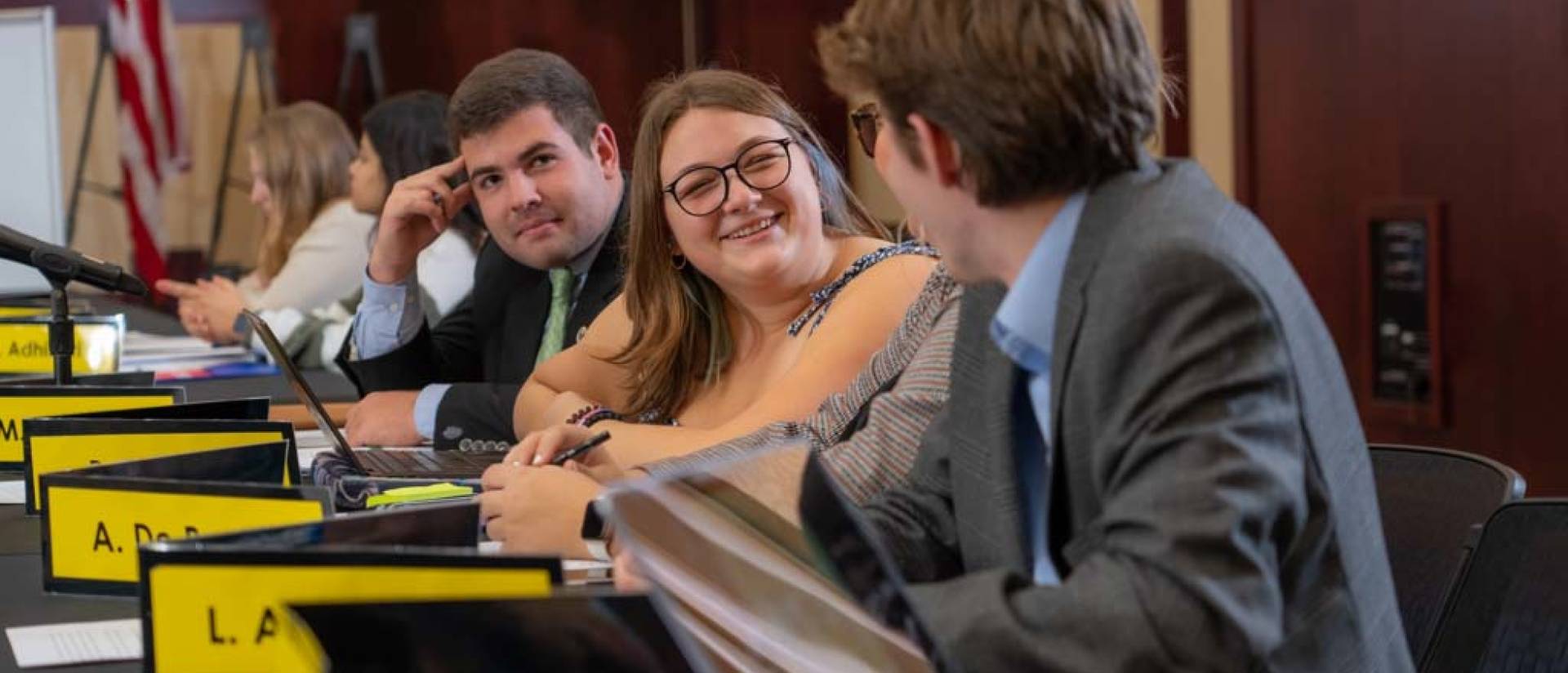 Student Senate in session, female student facing camera, smiling, all students seated at a skirted table