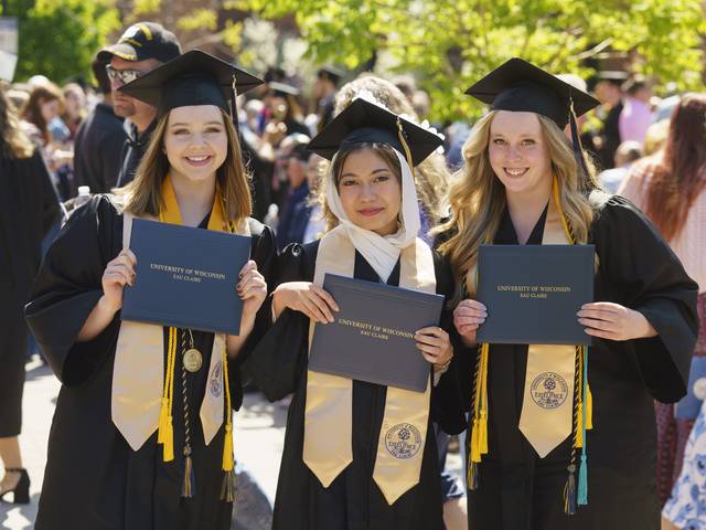 three women graduating at UWEC, in caps and gowns