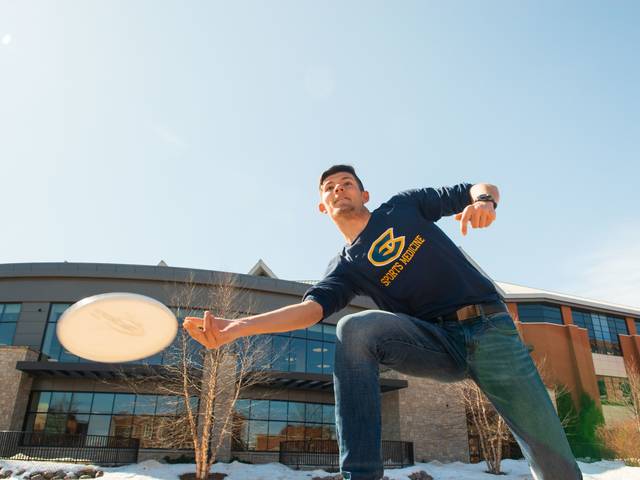 male student in Blugold long sleeve t playing frisbee
