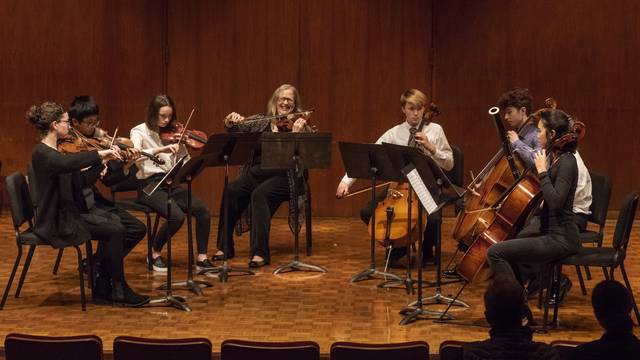 students in a small ensemble playing strings with an instructor
