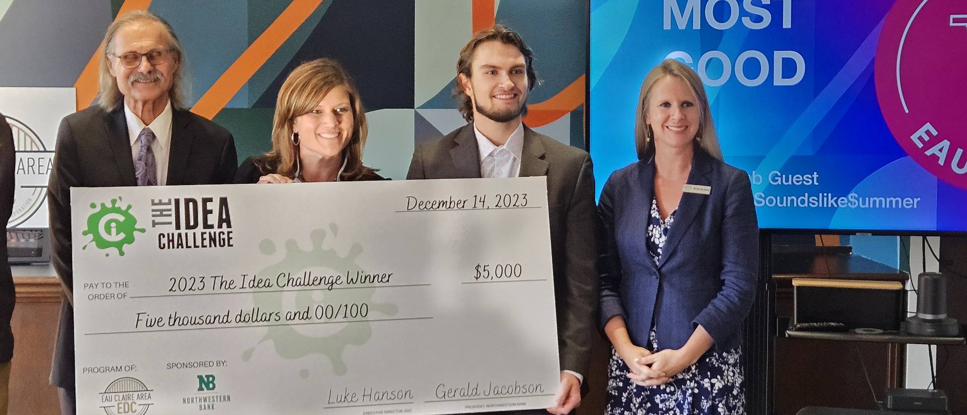 Four people standing behind an oversized check.