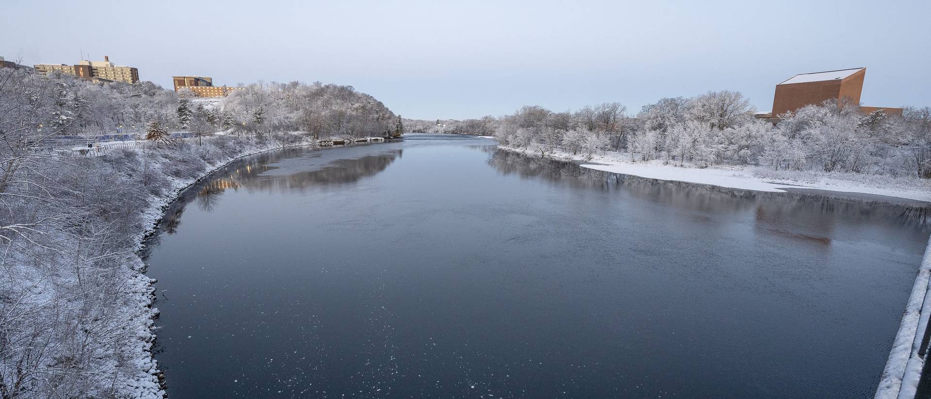 The Chippewa River in winter, with snow on the trees and buildings lining both sides of the river