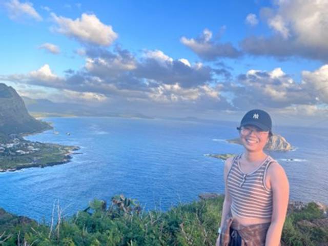Female student posing on a high Hawaiian shoreline over the sunset