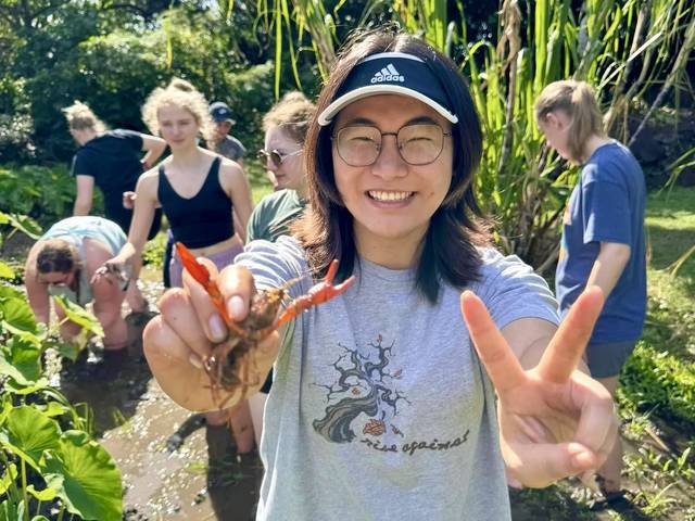 Yangguang Chen in Hawaii for immersion 2024, holding to shrimp toward camera