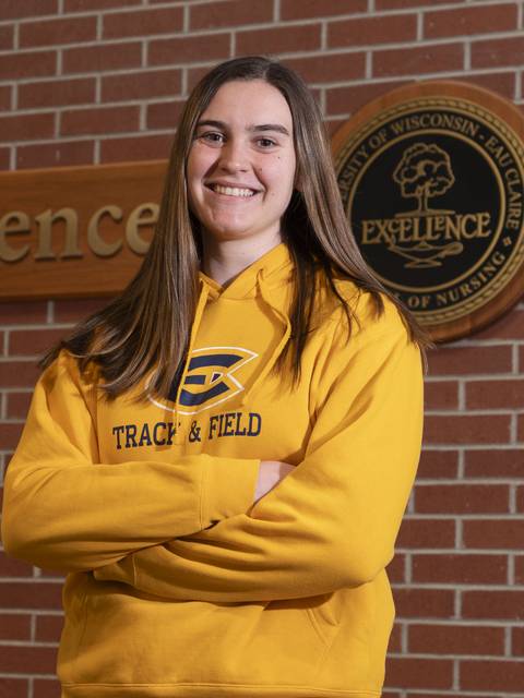 Track athlete poses in UWEC uniform with throwing gear.