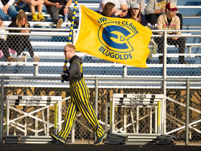 Blugold flag being held by fan in striped bibs at track meet