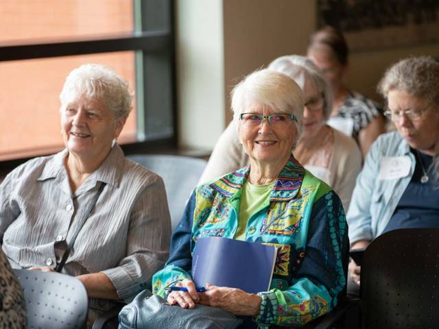 A group of Academy for Lifelong Learners sit and wait for a presentation