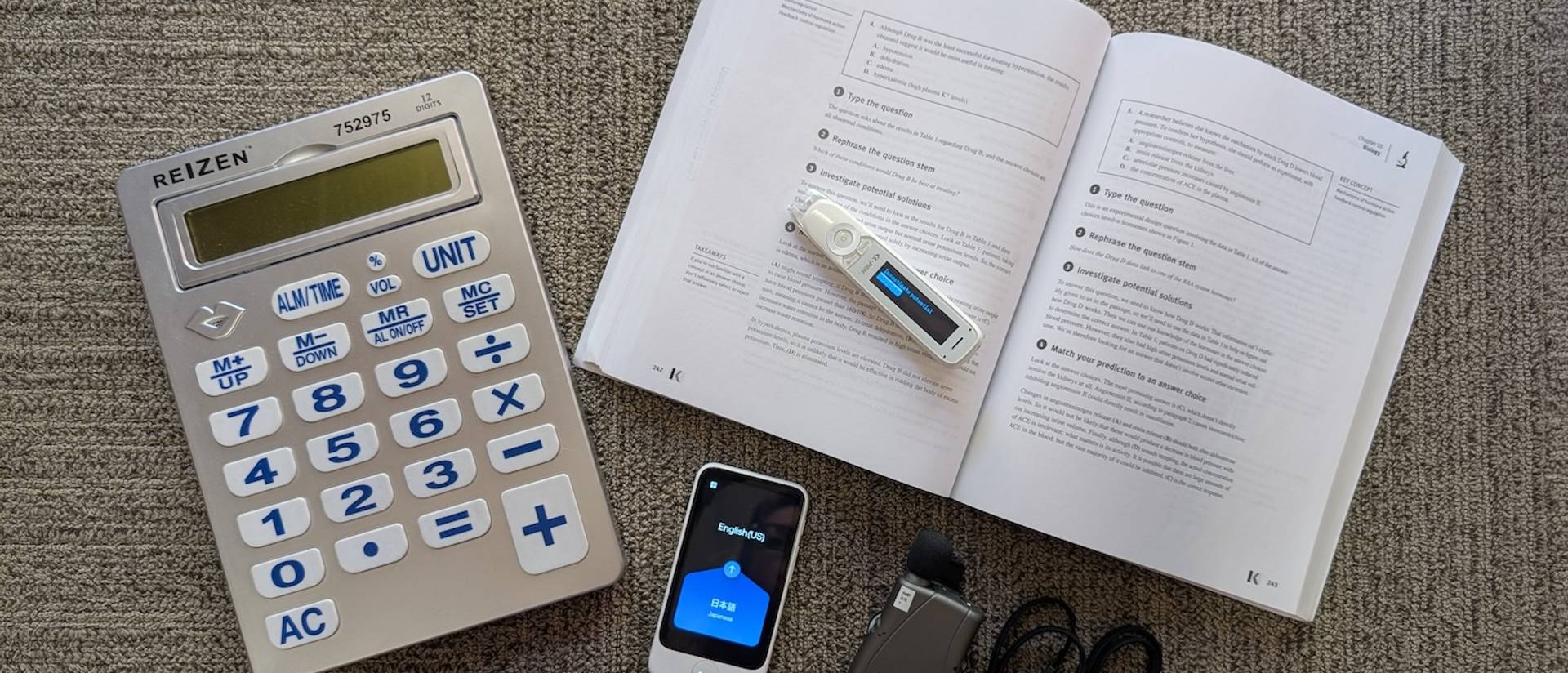 A talking calculator, text-to speech pen, pocket amplifier and a translator all arranged on a table.
