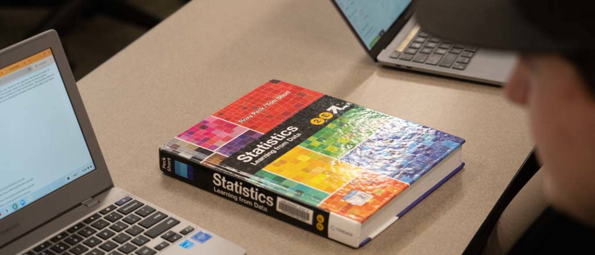 Photo of student with laptop and textbook