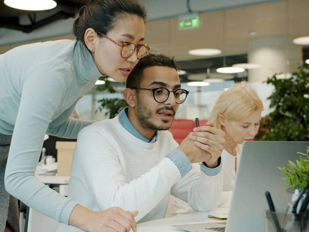 A group of employees around a computer discussing a strategy