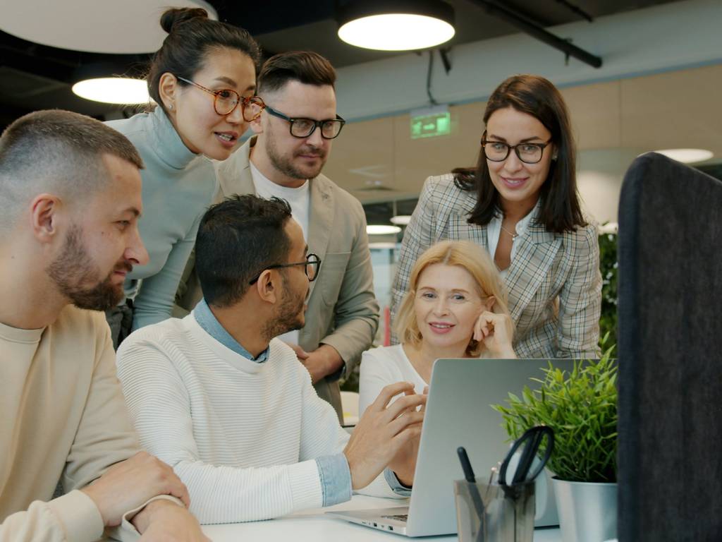A group of employees around a computer discussing a strategy