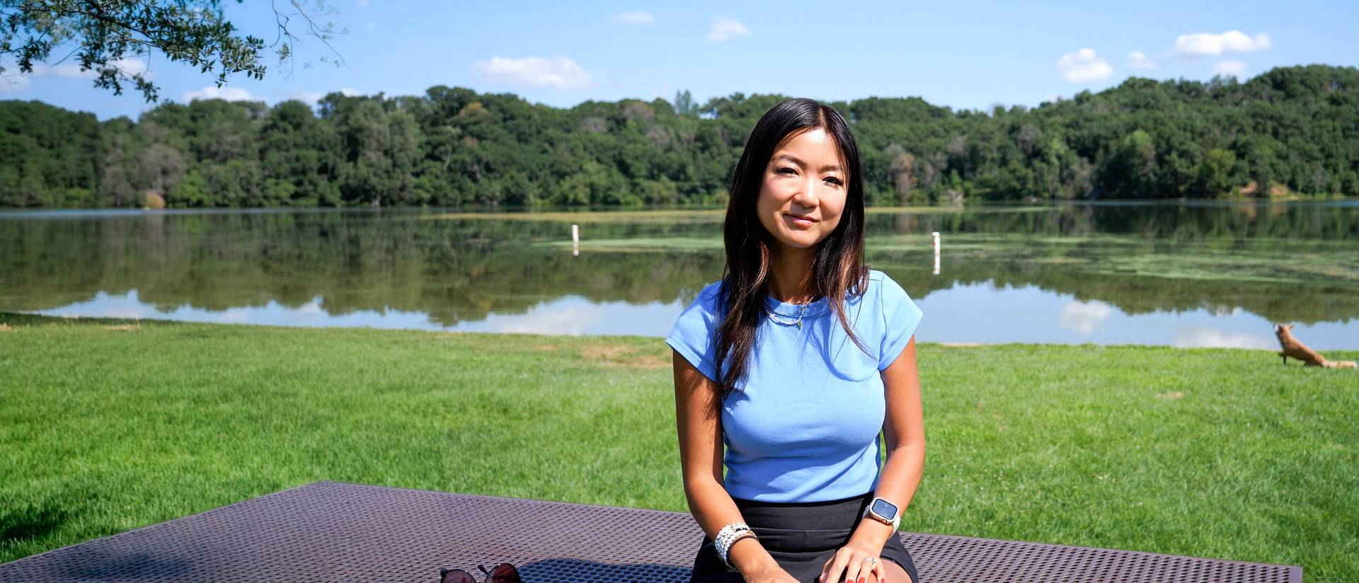 alumna Jenny Anderson sitting outside by a lake
