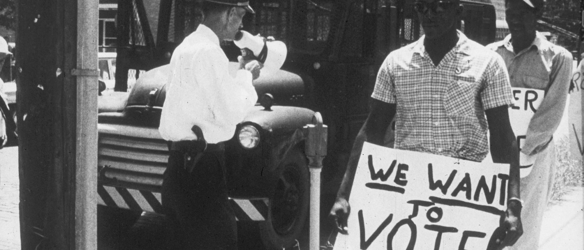 Historical photo from civil rights era, voting rights sign