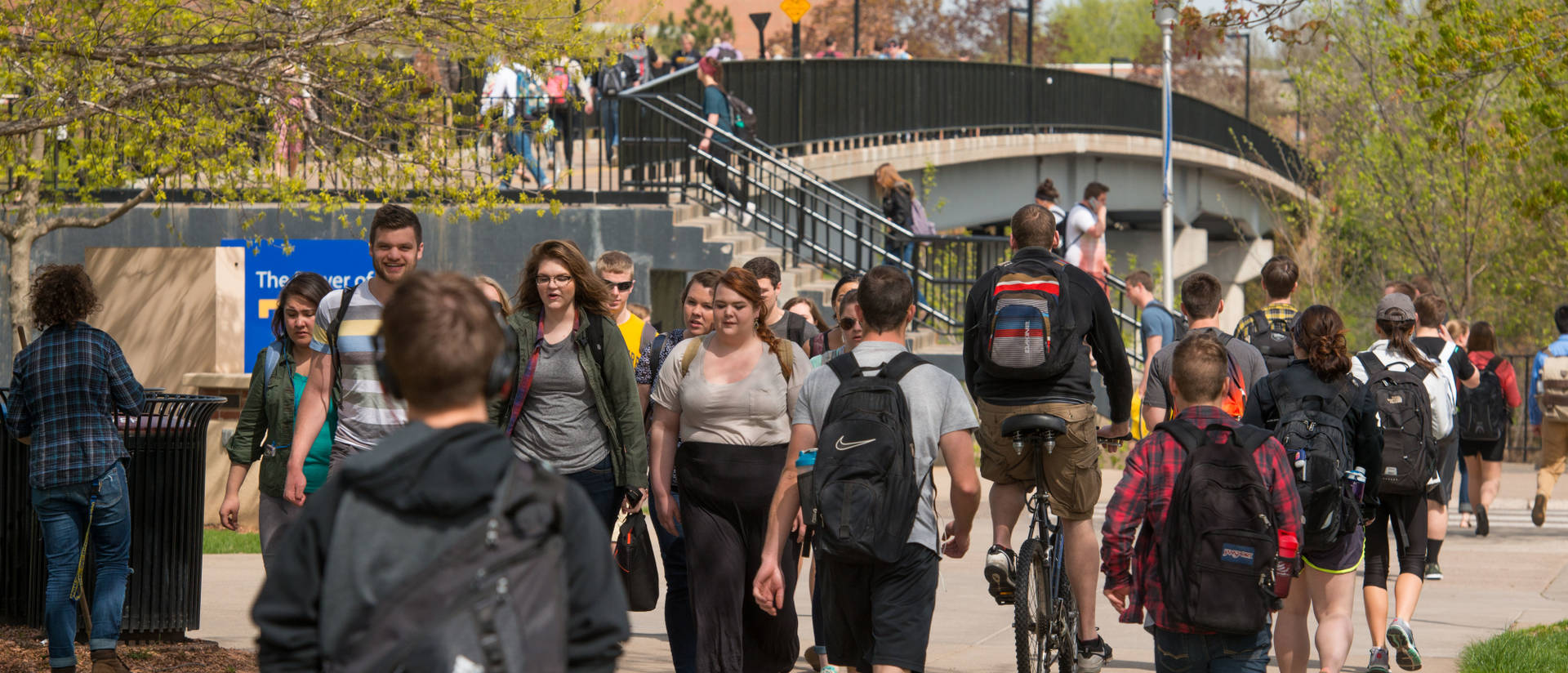Students walking on campus sidewalks and the campus footbridge