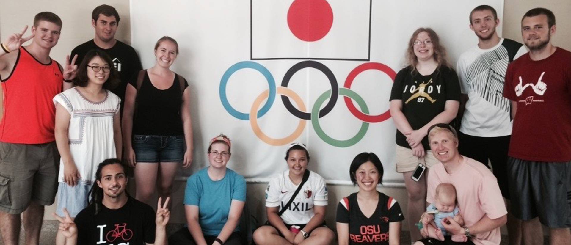 Kinesiology students gather around a screen with the Japanese flag and the Olympics logo during an immersion trip to Japan.