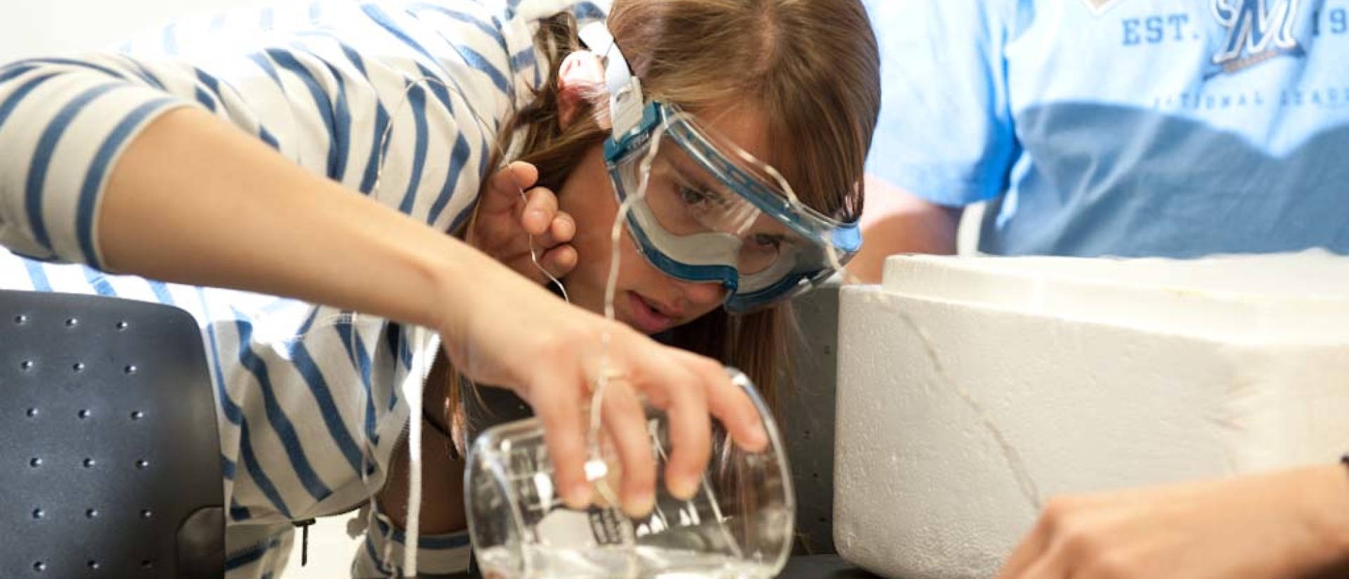 Student pours chemicals from graduated cylinder