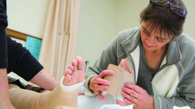 A nurse practices wrapping a foot as part of the Wound Treatment Associate clinical