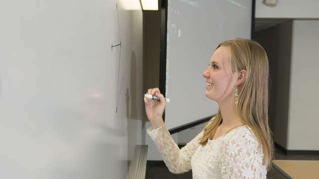 Professor writes on a white board