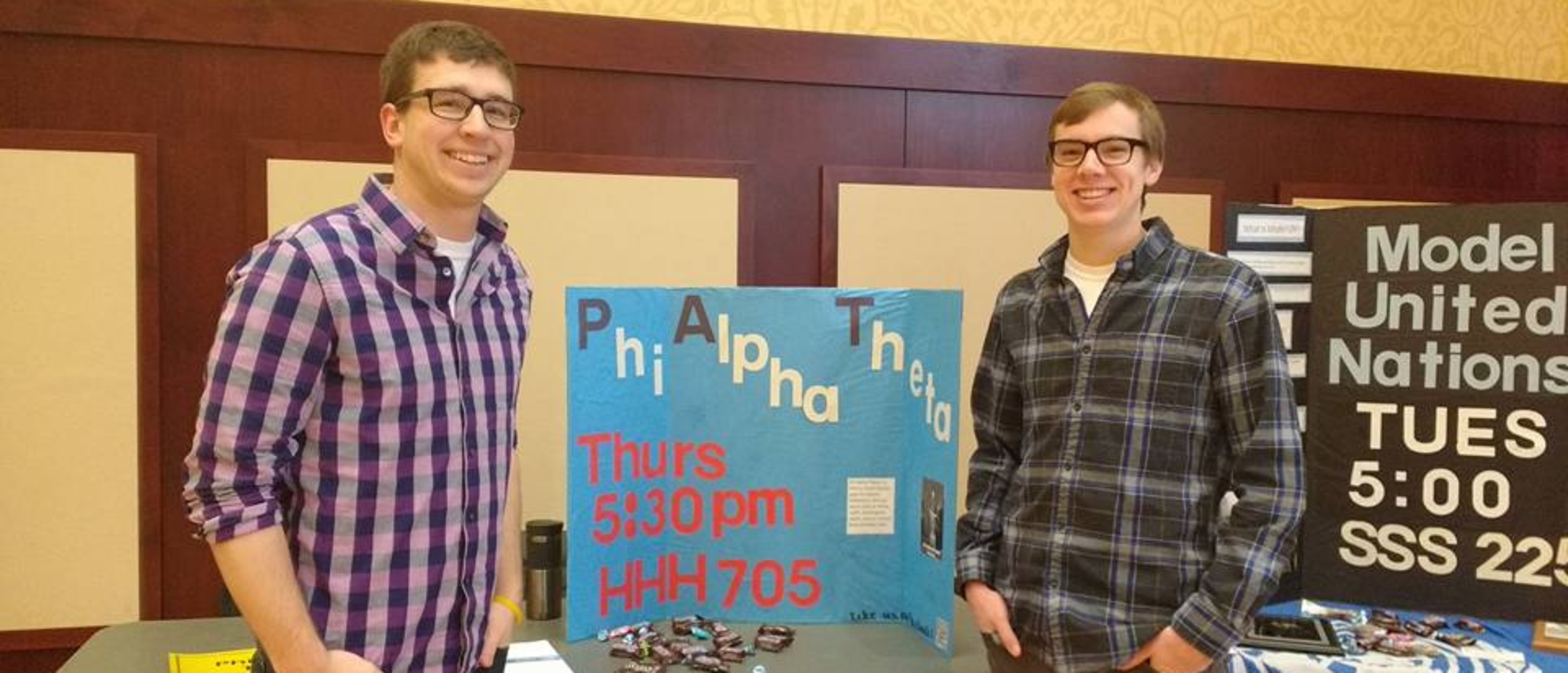 Students with the history student organization, Phi Alpha Theta, stand next to table display