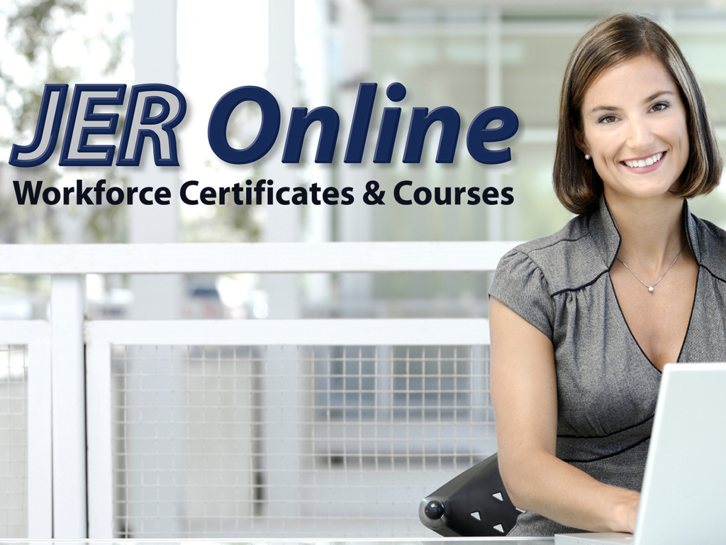 Woman smiling and sitting behind a desk with her hands on a laptop.