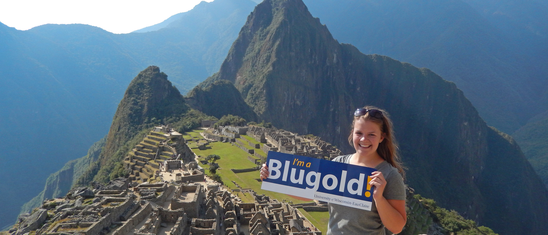 Student atop Machu Pichu in Peru holding I’m a Blugold sign.