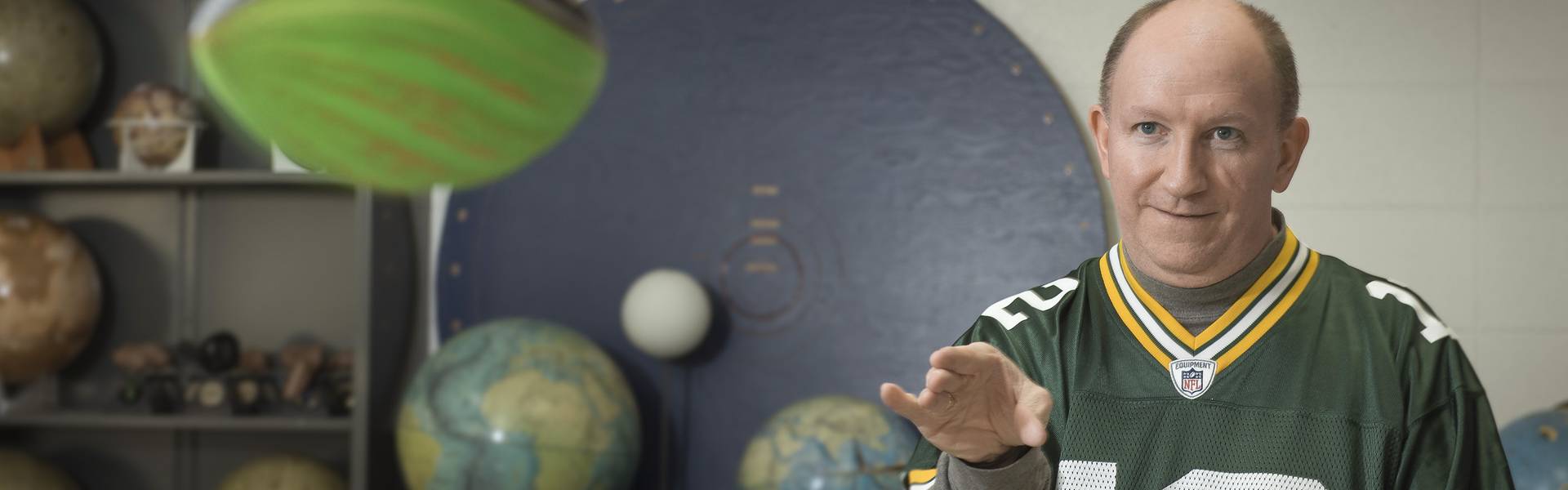 Dr. Erik Hendrickson throws a foam football while wearing a Green Bay Packers jersey.
