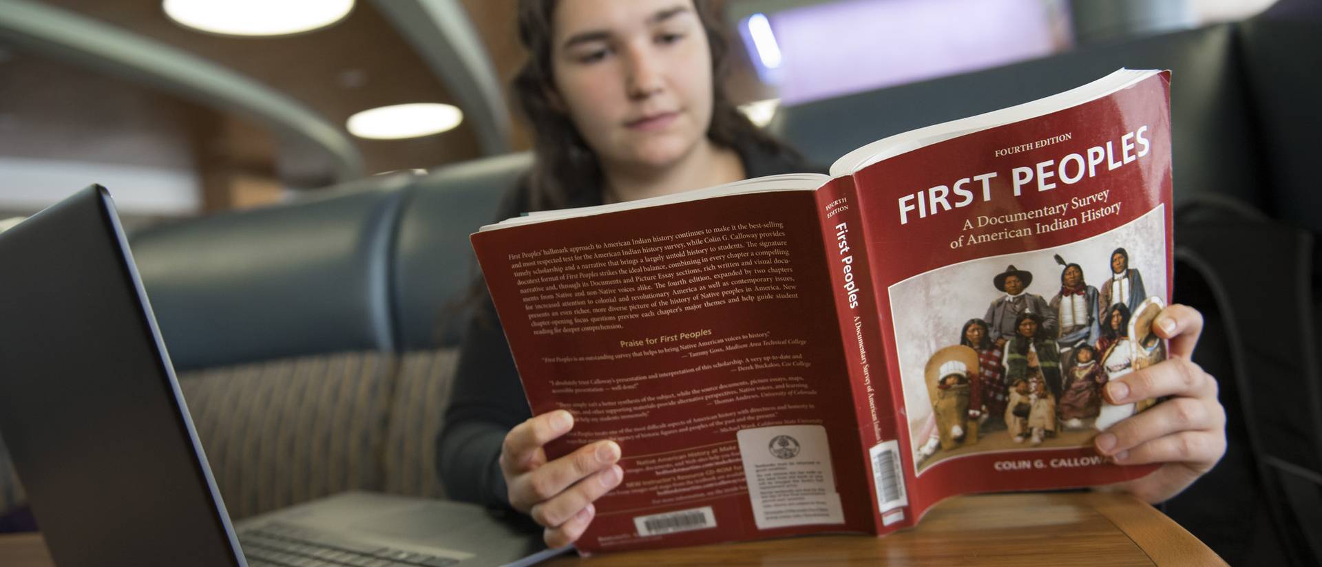 A student reads an American Indian Studies textbook in a Davies Center booth.