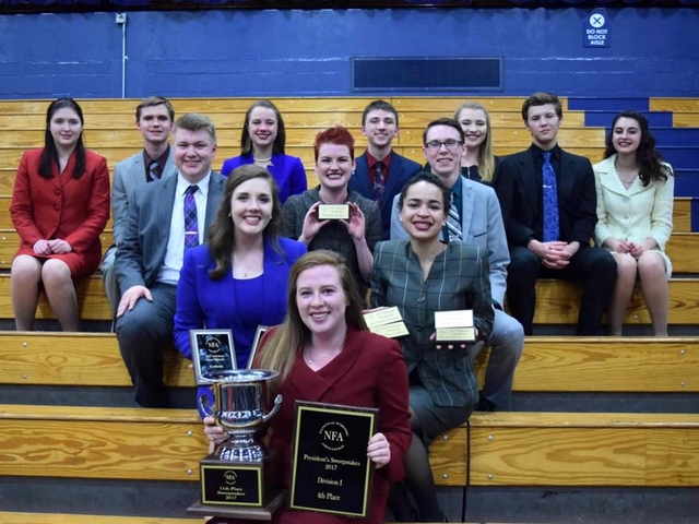 Forensics team at the 2017 NFA awards on the bleachers with their trophies.