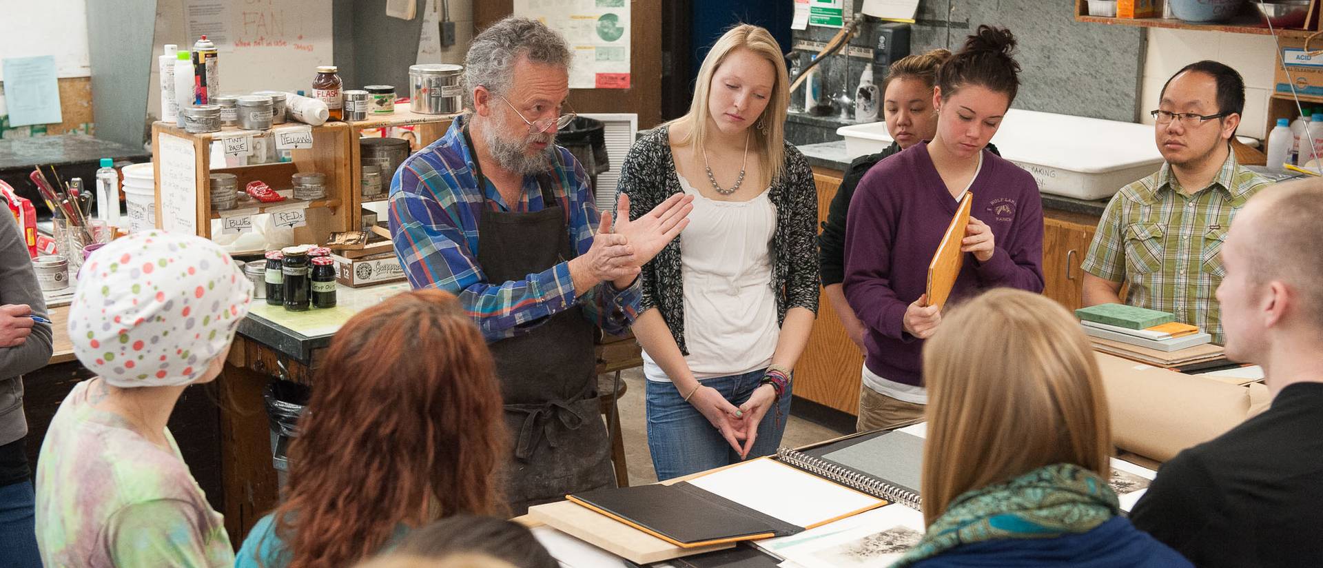 An artist speaks to students gathered around a table.