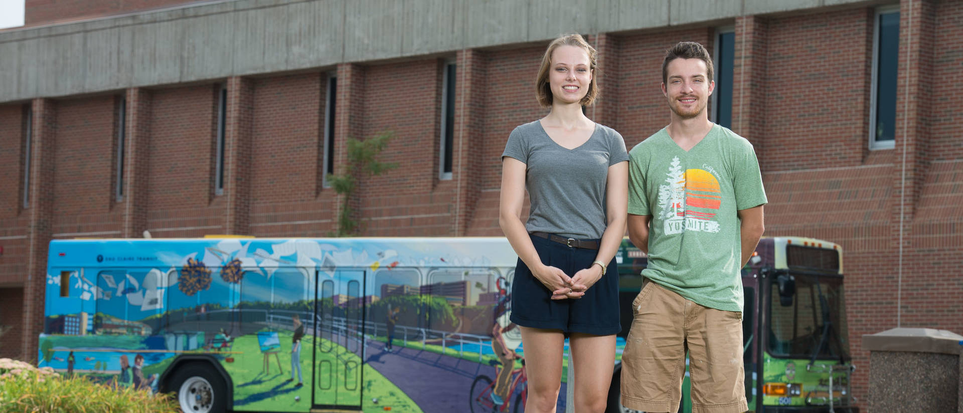 Roz Cashman and Lukas Carlson in front of Centennial Bus wrap. 