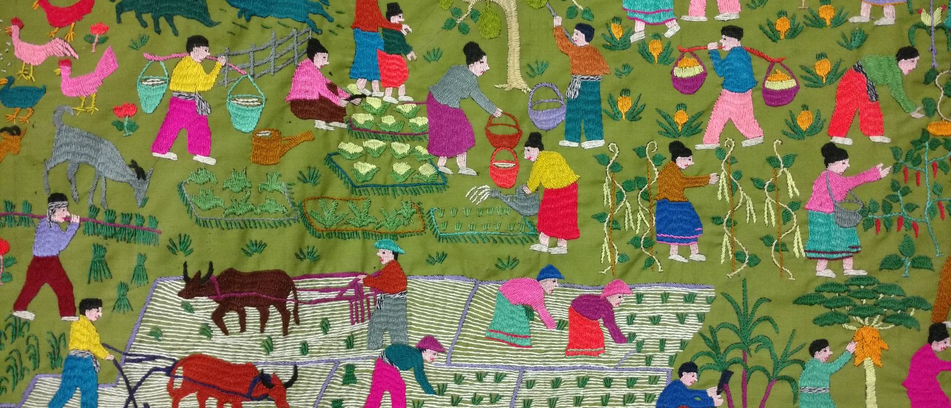 Close up of a story cloth that depicts people working on a farm.