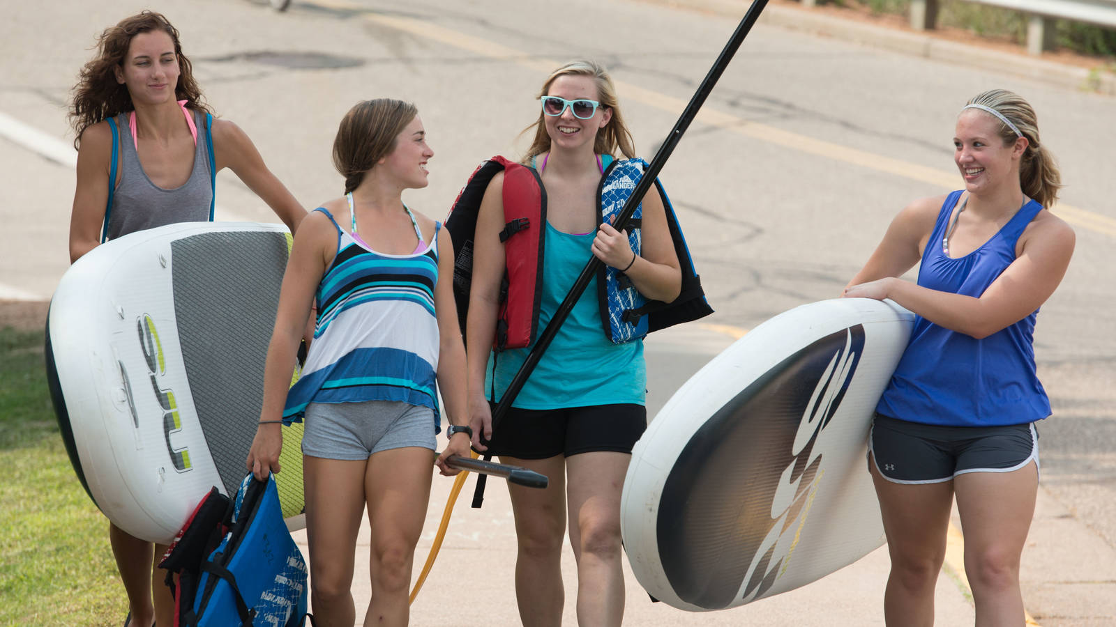 Students heading out to river float with rented paddle boards and tubes