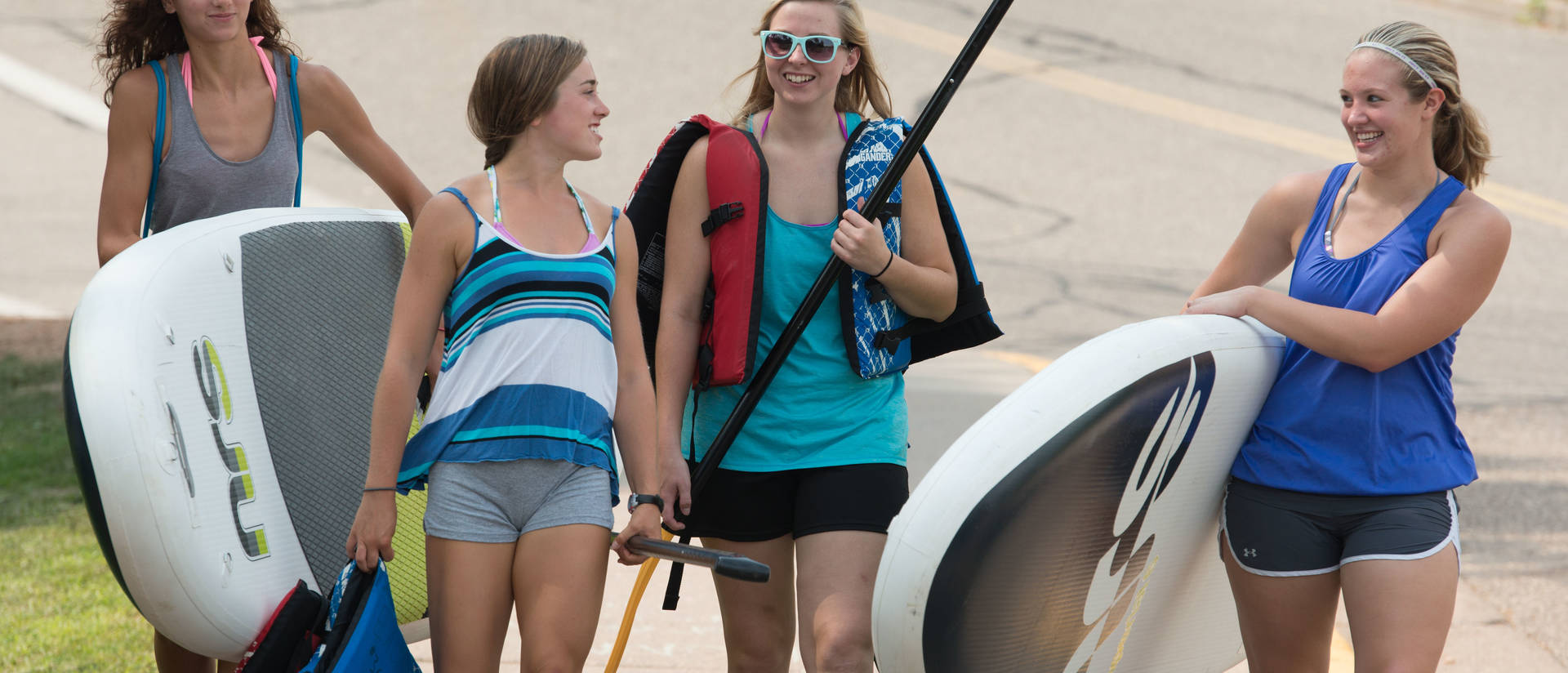 Students heading out to river float with rented paddle boards and tubes
