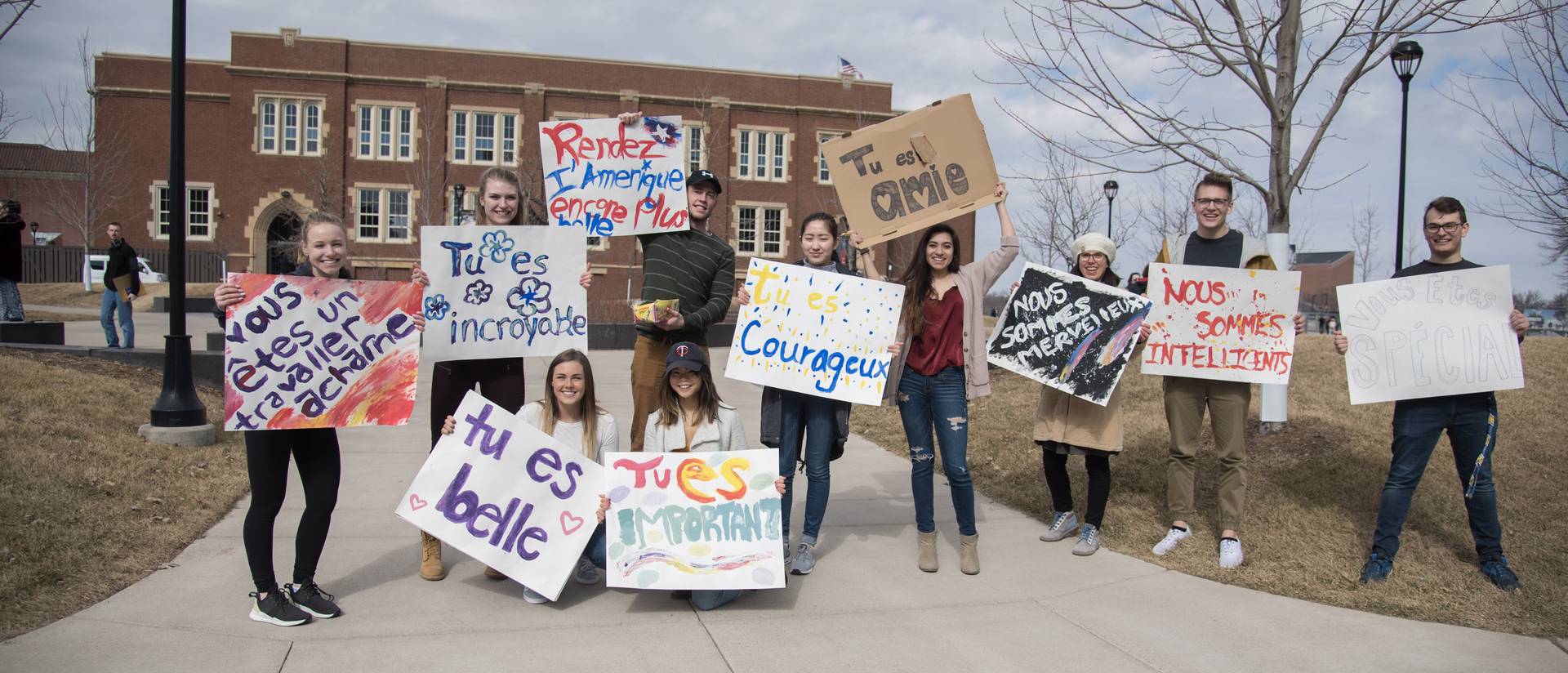 French students happily display posters with positive messages in French on the Campus Mall.
