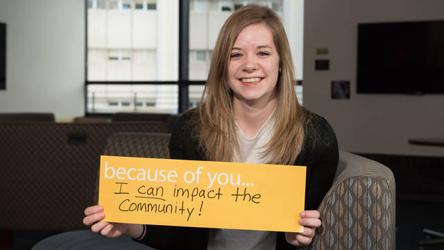 Girl holding sign that says: "Because of you, I can impact the community!"