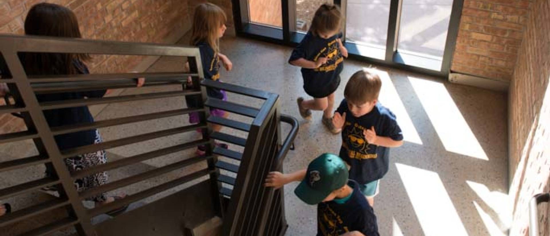 Children excitedly rush down a stairwell.
