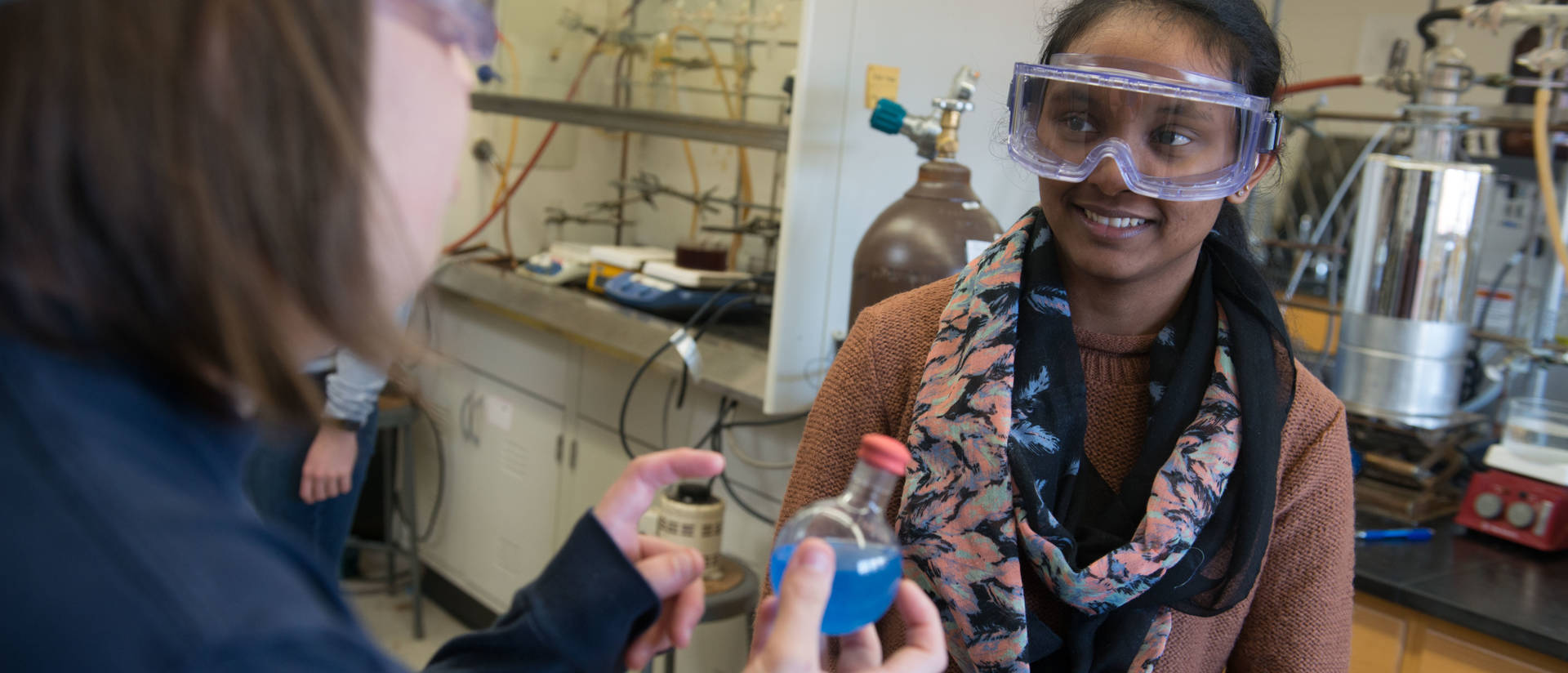 Two female students conducting research in polymers lab on campus
