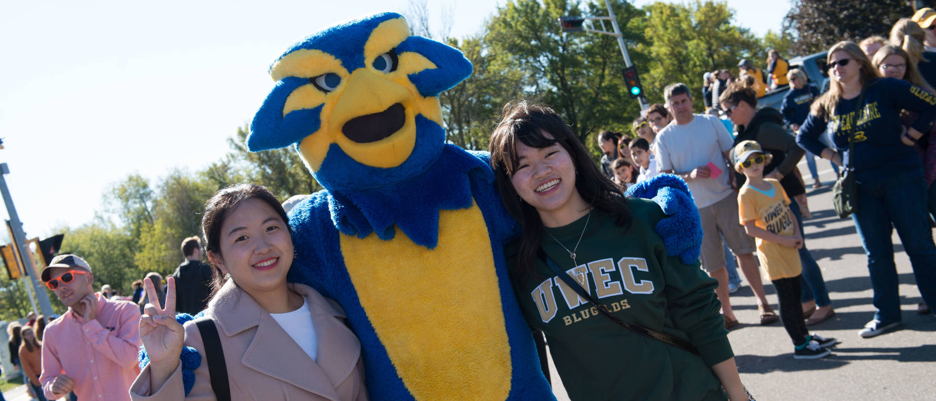 Blu the mascot poses with students at the 2017 Homecoming Parade